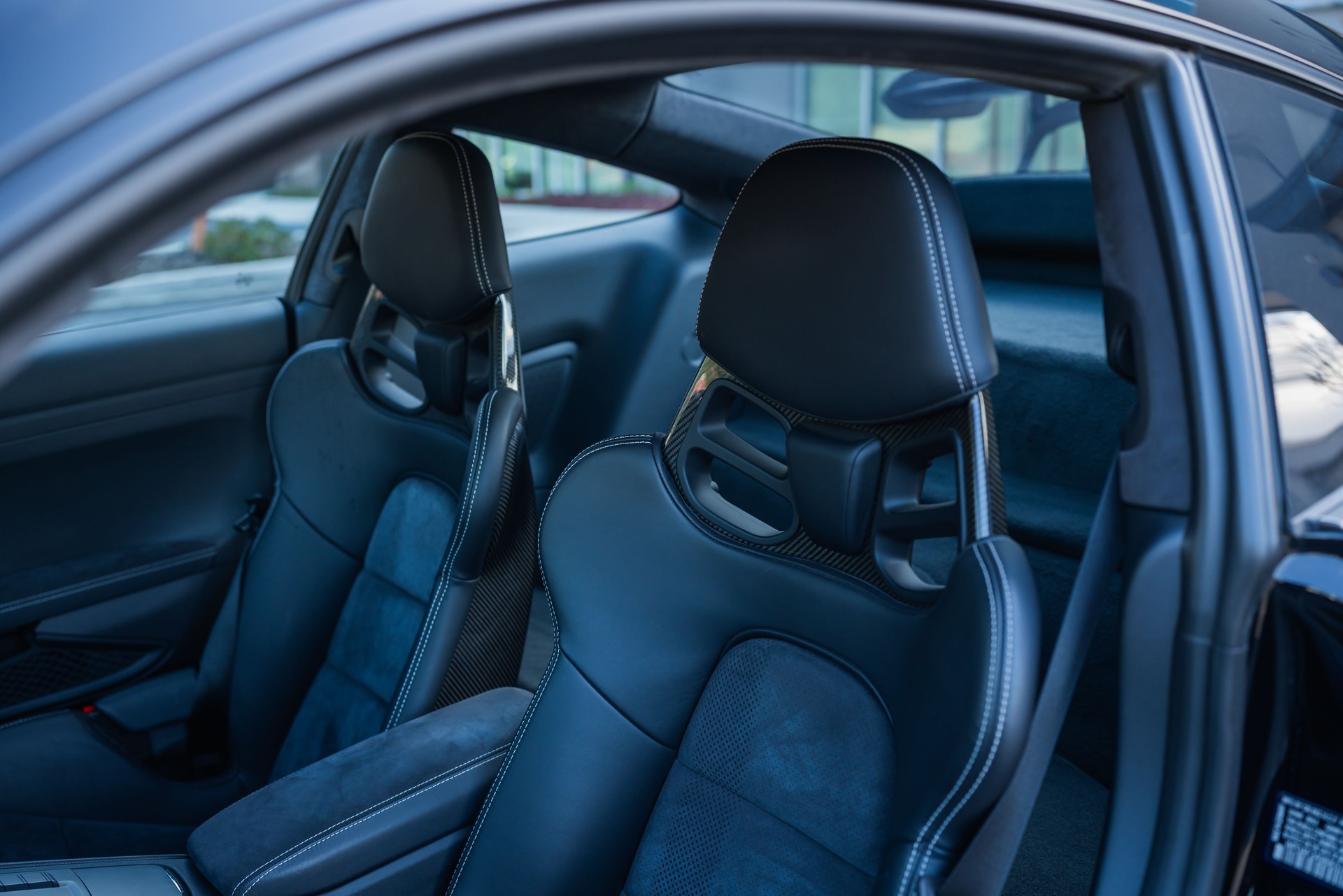 Front seats of a luxury sports car with carbon fiber detailing and premium stitching.