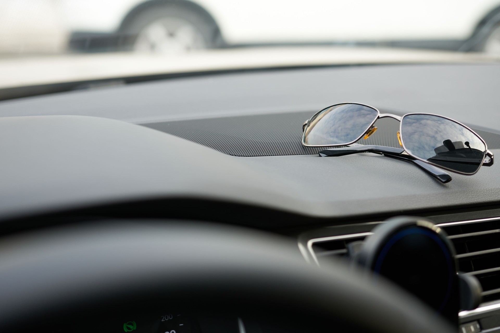 Close-up of sunglasses on the windshield of a sports car.